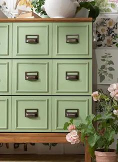 a green dresser with many drawers and flowers