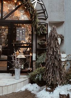 a store front with christmas decorations and lights on the windows, along with an evergreen tree