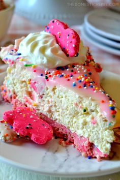 a piece of cake with sprinkles and pink frosting on it sitting on a plate