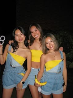 three young women standing next to each other in overalls and one holding a pair of scissors