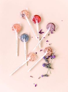 four lollipops are sitting on the table next to some lavender sprigs