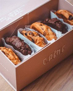 a box filled with assorted chocolate muffins on top of a wooden table