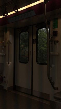 an empty train car with the doors open and trees in the backgrouund