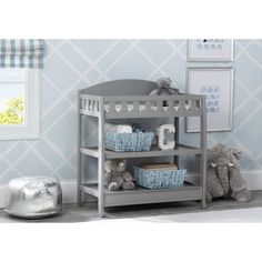 a baby crib with stuffed animals on the bottom shelf and blue wallpaper behind it