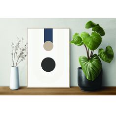 an art print on a shelf next to two potted plants and a plant in a vase