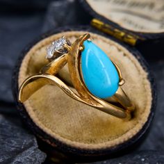 a gold ring with a turquoise stone in the middle and a diamond on it's side