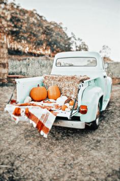 an old truck with pumpkins and blankets on the back