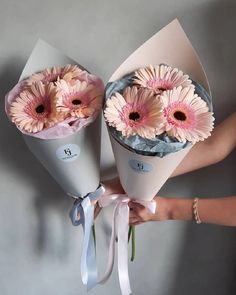 two bouquets of pink flowers are being held by someone's hand and wrapped in white paper