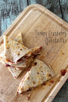 a wooden cutting board topped with three quesadillas