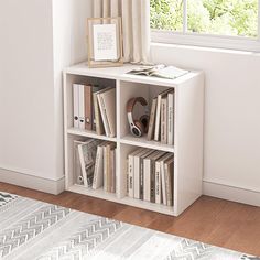 a white book shelf with books on top of it next to a window in a room