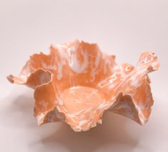 an orange flower shaped bowl sitting on top of a table