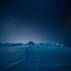 the night sky is full of stars and some snow covered hills are in the foreground