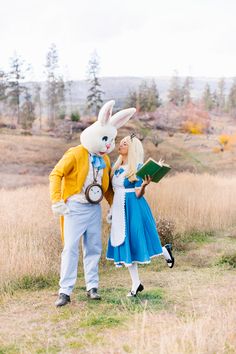 two people dressed up as peter rabbit and alice in the grass with an open book