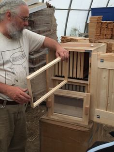 a man standing next to a pile of wooden crates in a room filled with stacks of boxes