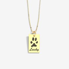 a necklace with a dog's paw on it and the word lucky written in black ink