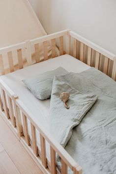 an empty crib with two pillows and a seashell on the bottom half of it