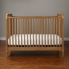 a wooden crib sitting on top of a hard wood floor next to a wall