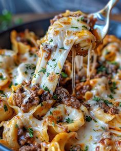 a fork full of pasta with meat and cheese on it, being lifted from a bowl