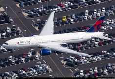 an aerial view of a delta airlines plane parked in a parking lot full of cars