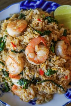 rice with shrimp and spinach served on a blue and white plate next to a lime wedge