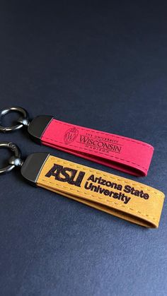 two keychains with the words arizona state university on them sitting next to each other