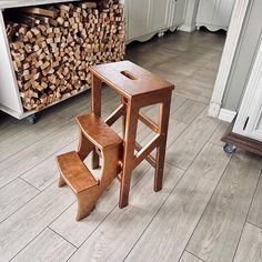 a small wooden table and stools in a room with wood stacked on the floor