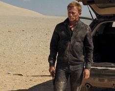 a man standing next to a car in the desert