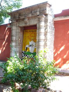 an old building with a painting on the front door and trees in the foreground