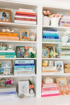 a white bookcase filled with lots of books and vases on top of it