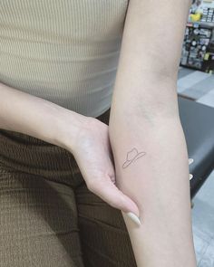 a woman with a small tattoo on her arm holding onto the other side of her arm