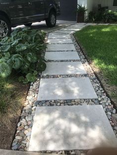 a black truck parked in front of a house next to a stone path that has plants growing on it