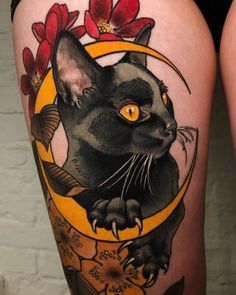 a woman's thigh with a black cat and flowers on it