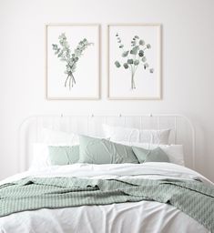 two paintings on the wall above a bed in a room with white sheets and pillows