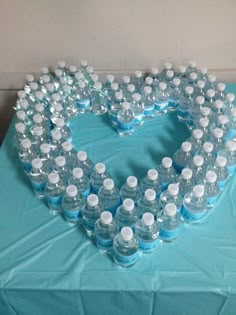 a heart made out of water bottles sitting on top of a blue tablecloth covered table