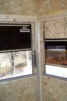 two windows in the side of a building that is being built with plywood boards