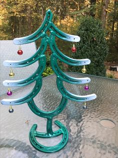 a christmas tree made out of horseshoes sitting on top of a table in front of trees