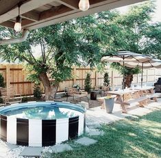 an outdoor hot tub with chairs and umbrellas in the back yard next to a tree