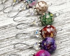 five different colored glass beaded earrings sitting on top of a wooden table