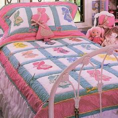 a bed with pink and blue bedspread, teddy bears and other items on it