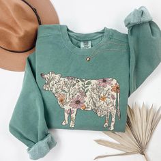 Comfort Colors® Cow Sweatshirt, Wildflowers Cow Farm Sweater, Heifer Cow Shirt, Cow Lover Gifts, Floral Cows Tshirt, Fall Crewneck, Cow Gift ABOUT: ⋒ The sweatshirt used is the Comfort Colors® 1566 Unisex Garment-Dyed Sweatshirt ⋒ 80% ring-spun cotton, 20% polyester ⋒ Medium-heavy fabric ⋒ Relaxed fit ⋒ Sewn in twill label SIZING: ⋒ Sweatshirts are UNISEX so please refer to sizing chart in photos ⋒ We recommend women to size down if between sizes. Men to size up if between sizes. ⋒ Oversized loo Cow Crewneck Sweatshirt, Fall Green Tops With Embroidered Graphics, Cotton Sweatshirt With Printed Relaxed Fit, Green Tops With Embroidered Graphics For Fall, Cotton Relaxed Fit Printed Sweatshirt, Green Embroidered Tops For Fall, Country Sweaters, Farm Sweater, Farm Sweatshirt