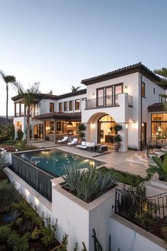 a large white house with a pool in the front yard and palm trees around it