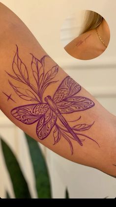 a woman's arm with a purple dragon tattoo on it and a green plant in the background