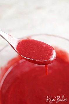 a spoon filled with red liquid sitting on top of a table