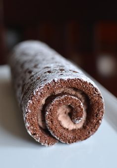 a rolled up chocolate pastry sitting on top of a white plate