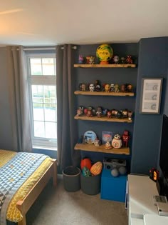 a bedroom with blue walls and shelves on the wall, along with toys in bins