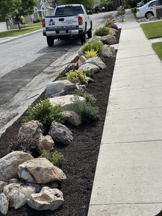 a white truck is parked on the side of the road near some rocks and flowers