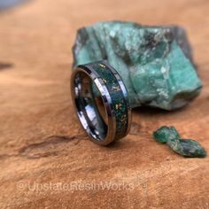 a wedding ring sitting on top of a wooden table next to a piece of rock