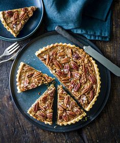 a pecan pie on a black plate with a knife and fork next to it