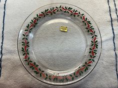 a clear glass plate with red, green and blue designs on the rim is sitting on a white tablecloth