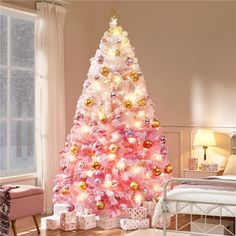 a pink christmas tree with gold ornaments in a bedroom